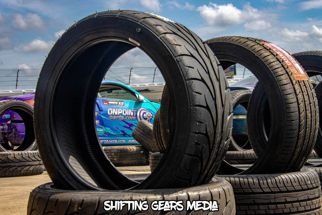 Drift tires stacked at Rockingham Speedway with an On Point Parts drift car in the background