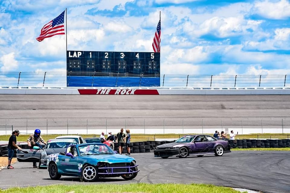 Drift cars at Rockingham Speedway with The Rock scoreboard in the background